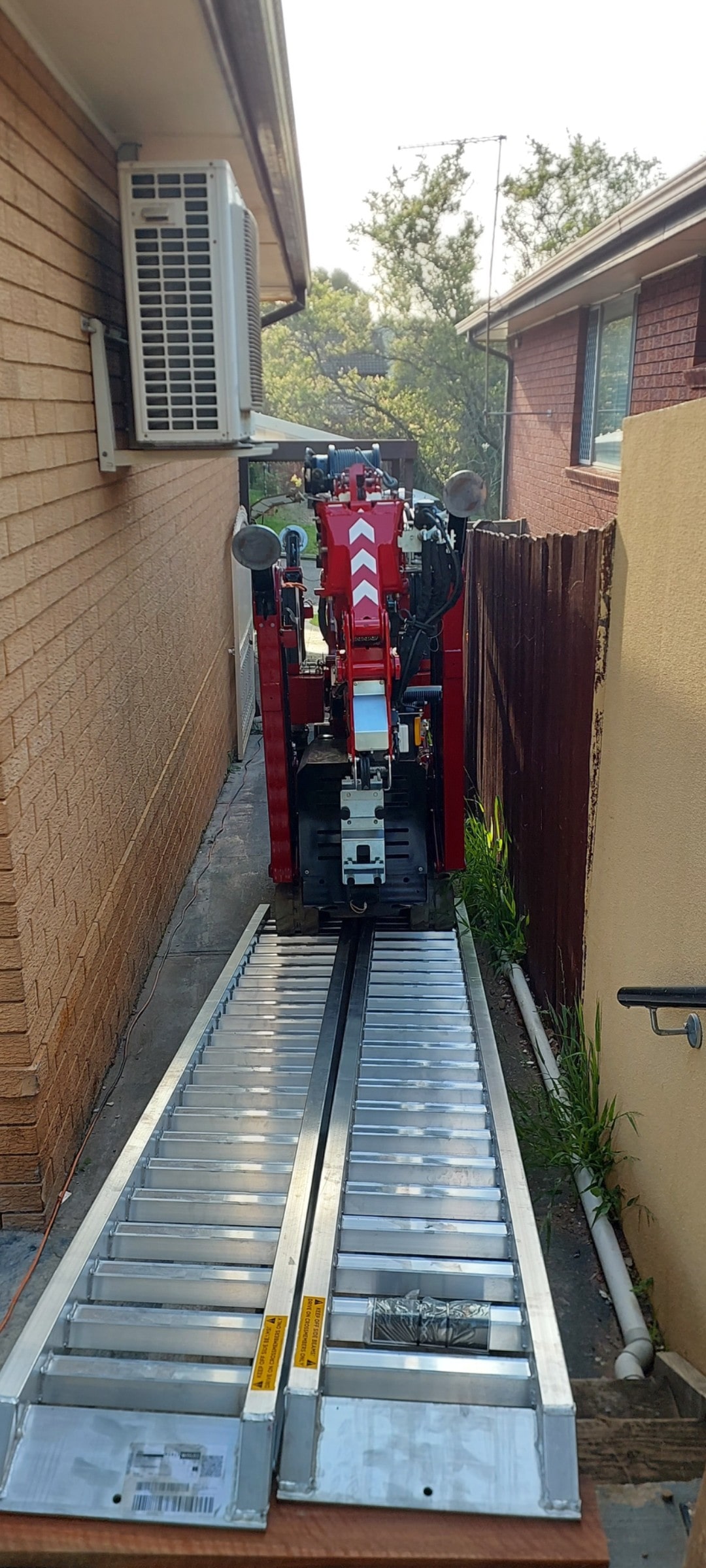 Hoeflon c6 Crane driving down side boundary of residential house.